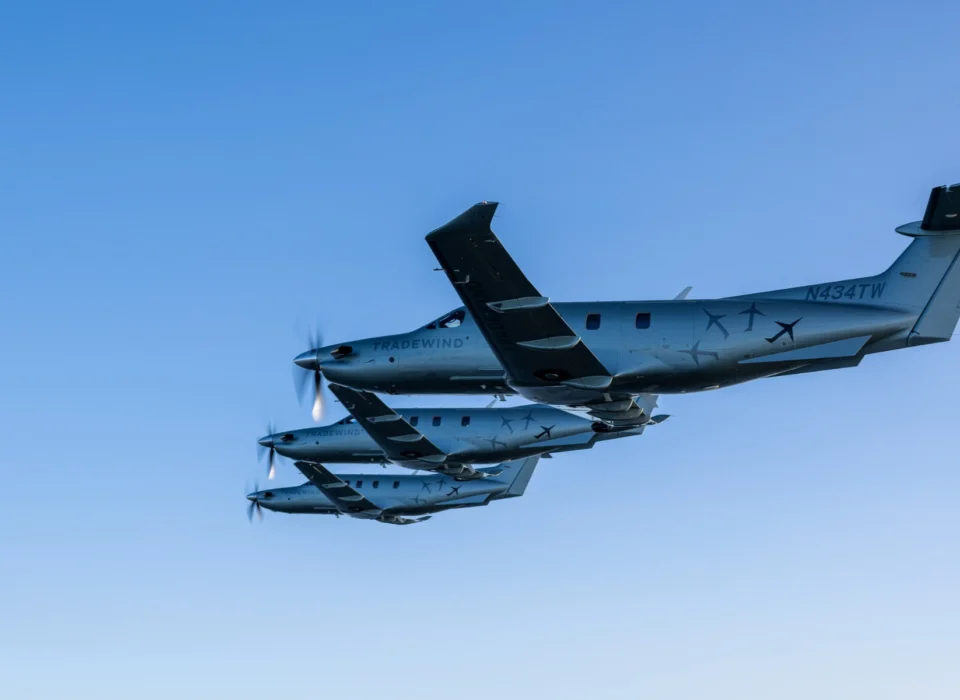 Three Tradewind PC-12s flying in formation against a clear blue sky.