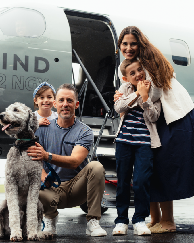A family of four with a dog in front of a Tradewind Pilatus private plane to a resort that allows dogs