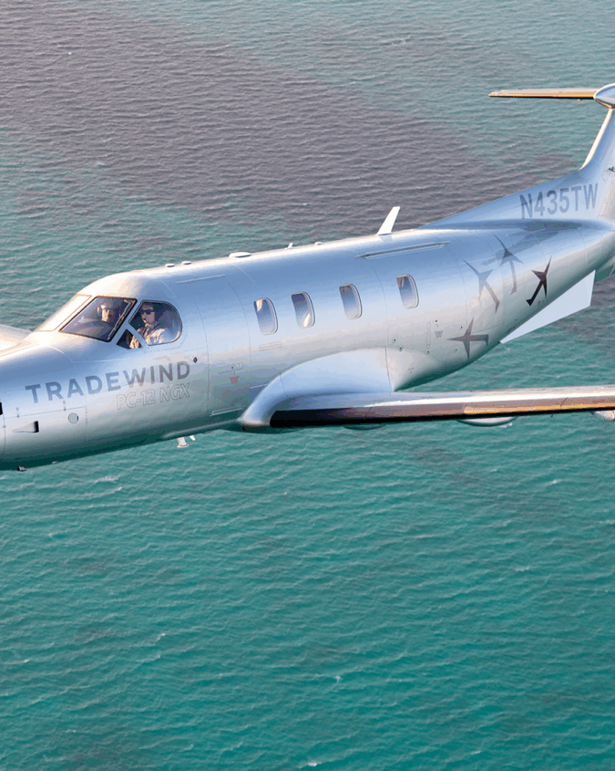 A Tradewind Pilatus plane flying to Nassau over blue water
