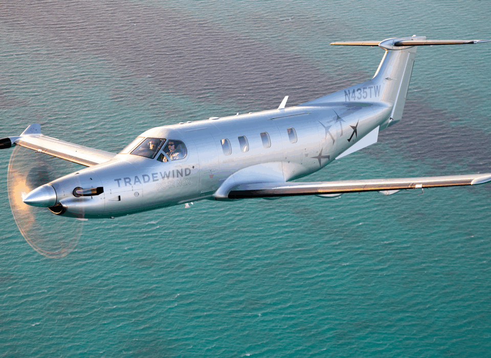A Tradewind Pilatus plane flying to Nassau over blue water