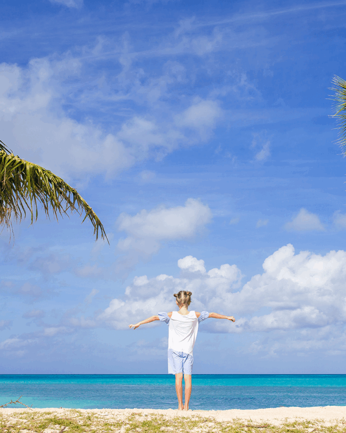 A girl posing in between two palm trees in The Bahamas