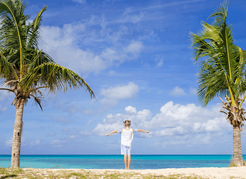 A girl posing in between two palm trees in The Bahamas