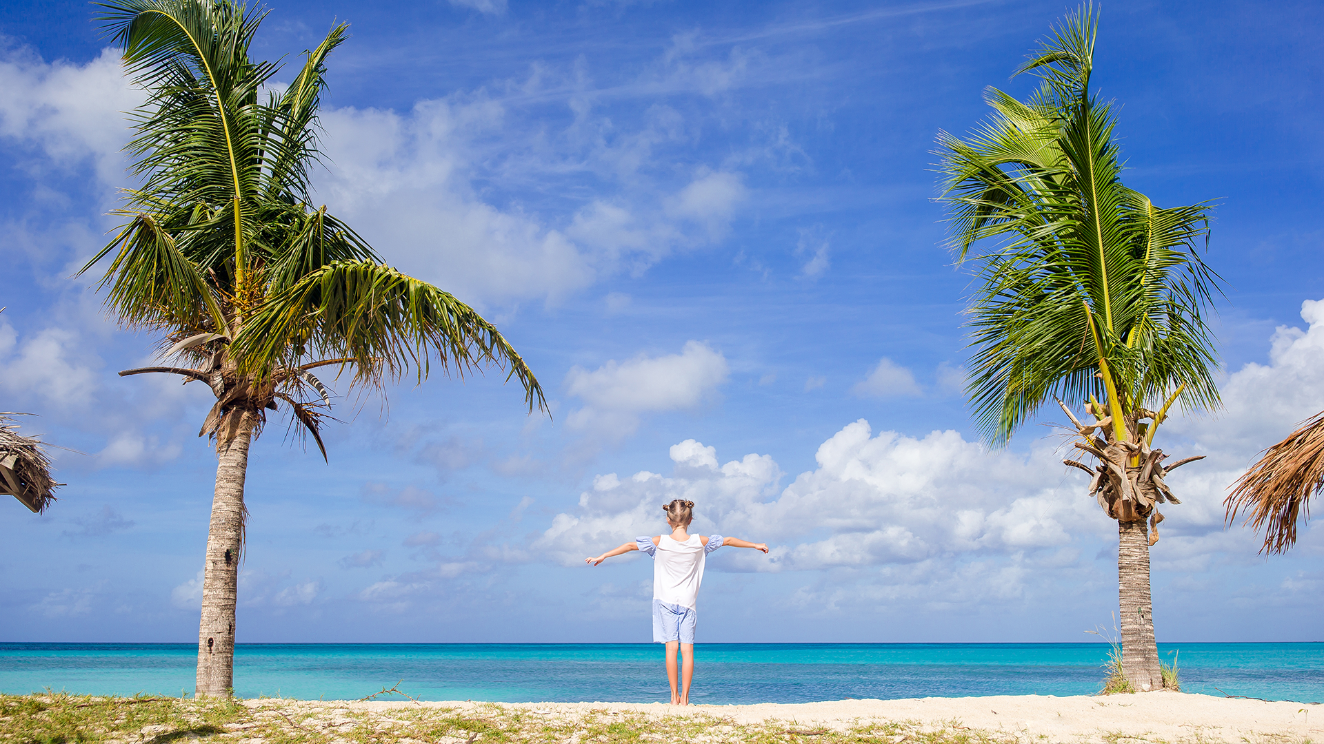 A girl posing in between two palm trees in The Bahamas