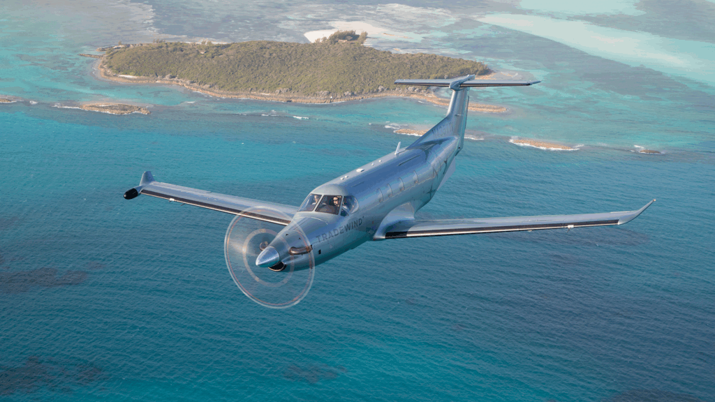 A plane flying over turquoise water during flights to The Bahamas