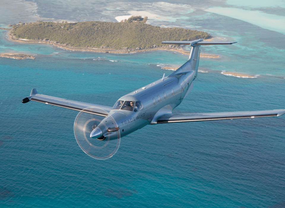 A plane flying over turquoise water during flights to The Bahamas