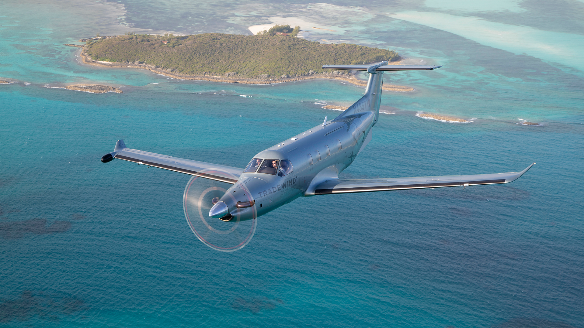 A plane flying over turquoise water during flights to The Bahamas