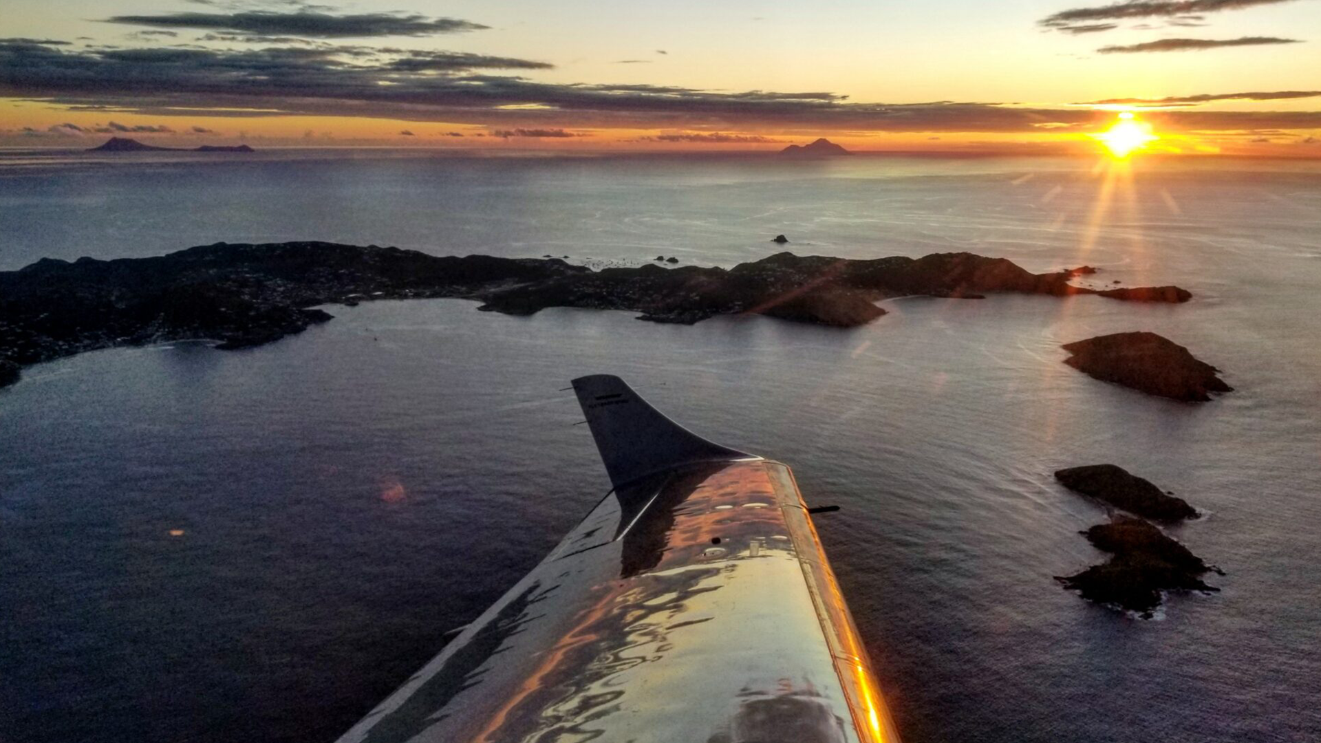 Plane wing views of San Juan islands in the Caribbean at sunset.