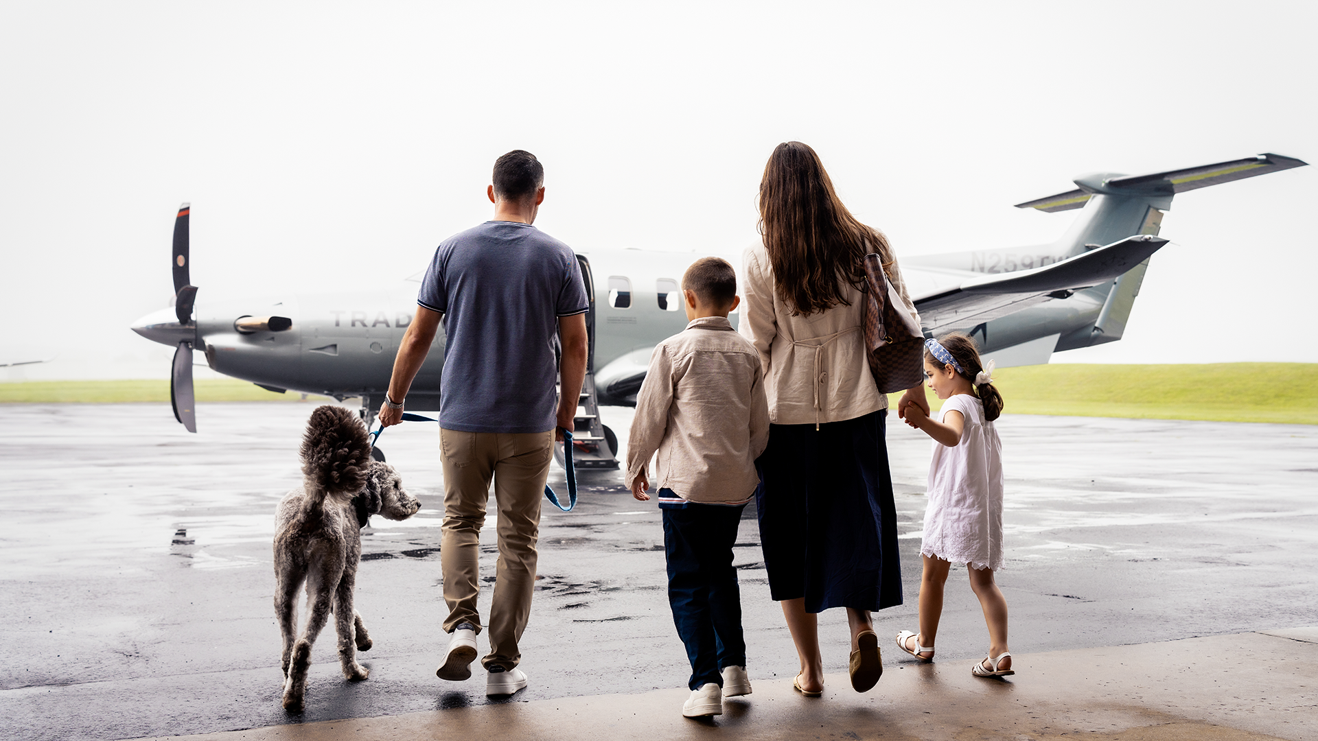 A family with their dog walking towards a Tradewind plane for flights to Nantucket.